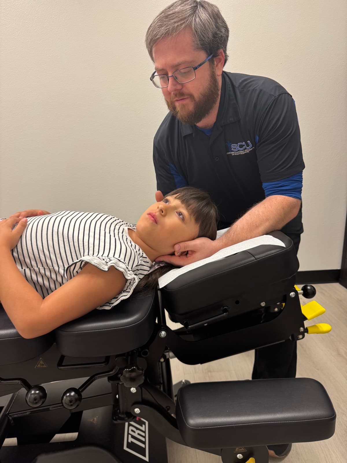 Dr. Smith performing a gentle neck adjustment on a young patient at Tailored Touch LV in Henderson, NV