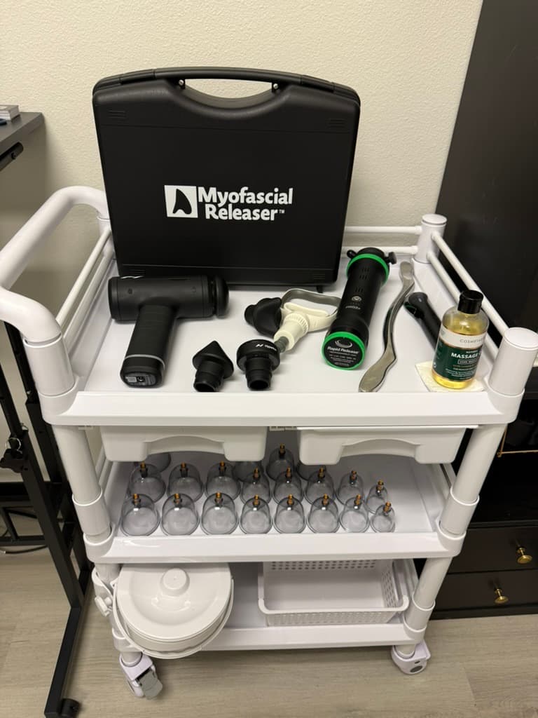 Treatment equipment at Tailored Touch, including a Myofascial Releaser, percussion gun, and cupping sets